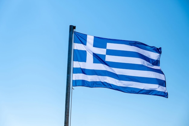 Die griechische Flagge schwingt vor blauem Himmel