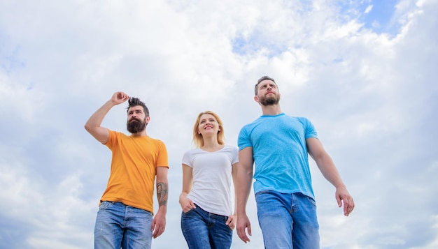 Die großartige Passform für den freien Tag Junge Menschen in lässigem Stil am bewölkten Himmel Gruppe von Menschen in Freizeitkleidung Modemenschen sehen im Sommeroutfit lässig aus Hübsche Frauen- und Männerfreunde, die im Freien spazieren gehen