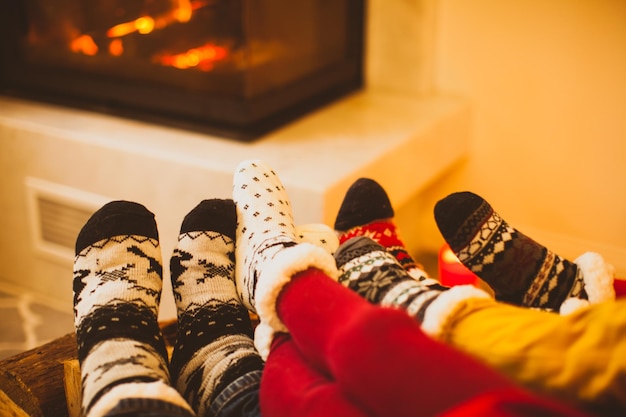 Die große Familie wärmt sich am kalten Wintertag am Kamin auf. Modernes Interieur, konzentrieren Sie sich auf die Socken