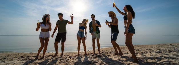 Die Gruppe von Freunden, die am Strand tanzen