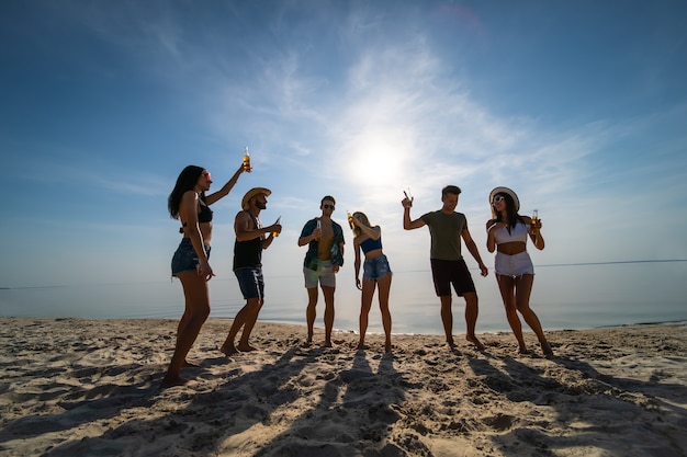 Die Gruppe von Freunden, die am Strand tanzen