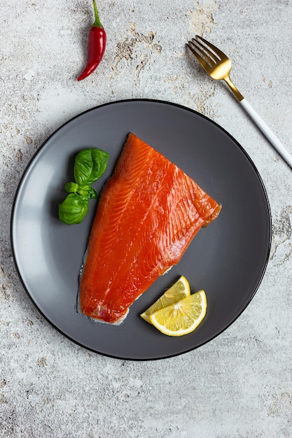 Die Hälfte des gesalzenen Lachsfilets auf einem grauen Teller Gesunde Ernährung