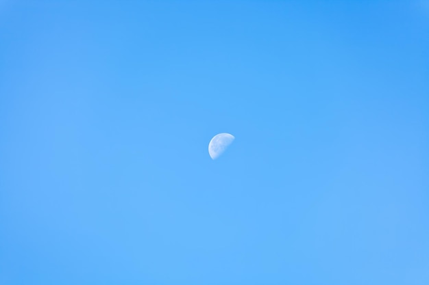 Die Hälfte des Mondes am klaren blauen Morgenhimmel