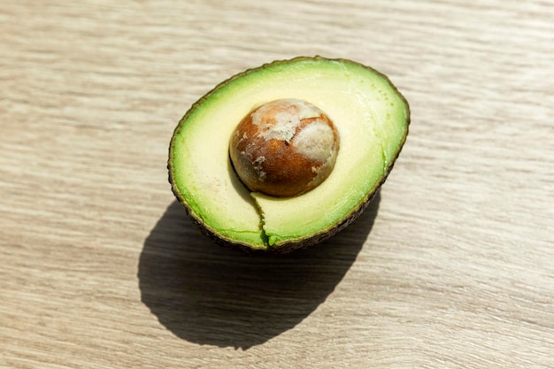 Die Hälfte einer frischen Haas-Avocado mit Kern auf einem Holztisch. Reife, nützliche Bio-Früchte, Nahaufnahme von oben