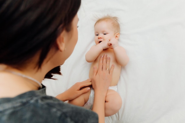Die Hände der Baby-Bauch-Massage-Frau massieren den Bauch des Babys