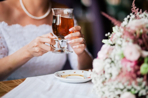 Die Hände der Braut mit dem Ehering, der die Tasse Tee aus nächster Nähe hält