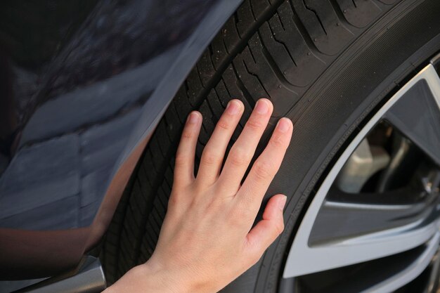 Die Hände der Fahrerin inspizieren den Radreifen ihres neuen Autos Fahrzeugsicherheitskonzept