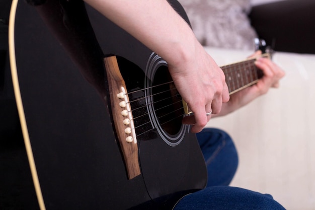 die Hände der Frau, die Akustikgitarre spielen