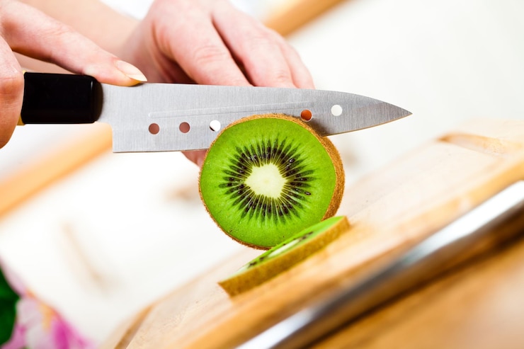 Foto die hände der frau schneiden frische kiwis in der küche
