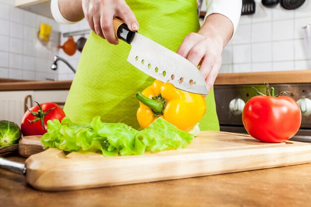 Die Hände der Frau schneiden frischen Paprika in der Küche