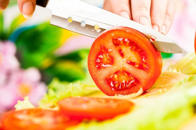 Die Hände der Frau schneiden Tomaten, ein scharfes Messer.