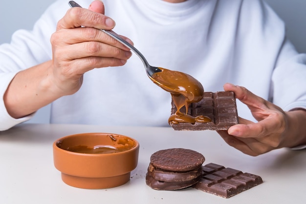 Die Hände der Frau setzen Dulce de Leche auf eine Schokolade, die nicht für Diabetiker geeignet istxA