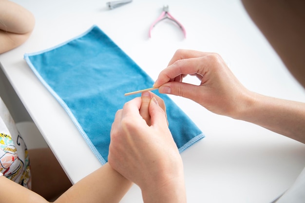 Die Hände der Frauen auf der Hand eines Kindes feilen ihre Nägel mit einer Nagelfeile Draufsicht flach liegend