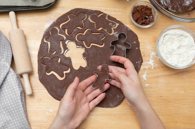 Die Hände der Frauen, die festliche Weihnachtslebkuchenplätzchen kochen. Schokoladenplätzchen oder Nachtisch kochen.