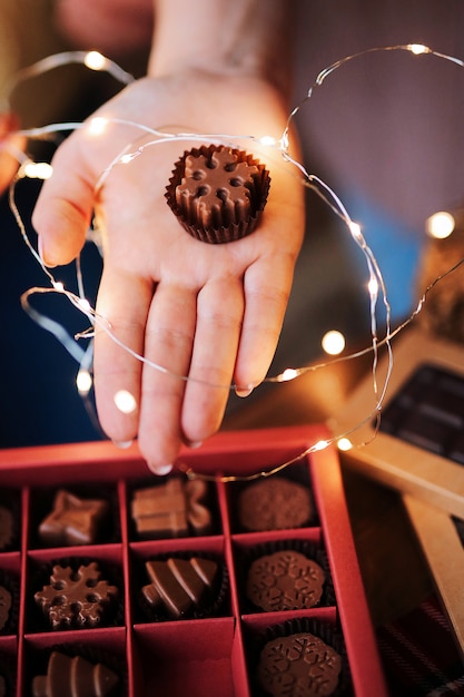 Foto die hände der frauen halten eine schöne weihnachtsschachtel mit natürlichen milchschokoladen, die in form von schneeflocken handgemacht sind