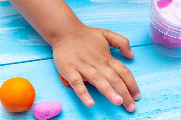 Die Hände der Kinder formen bunte Teignahaufnahme. Kindheitskindheit scherzt Babybildungskonzept