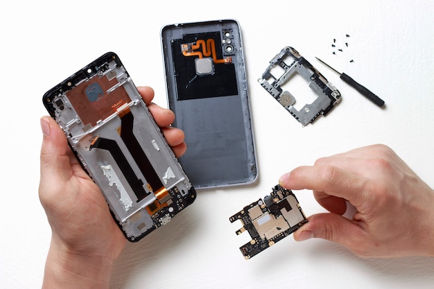 Die Hände der Männer halten einen Schraubenzieher in ihren Händen und reparieren defektes Smartphone