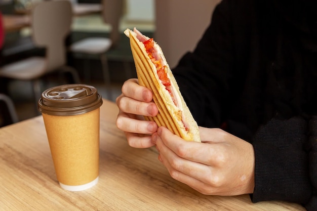 die hände der männer halten fast food, burritos in ihren händen morgens frühstückskaffee in der tasse