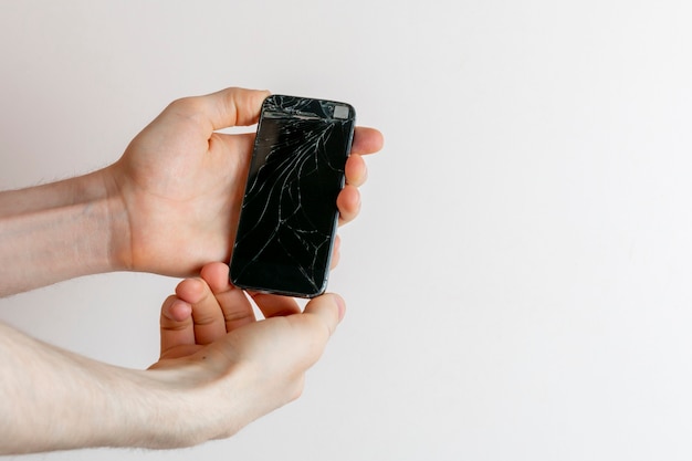 Die Hände der Person, die ein abgestürztes, kaputtes Handy halten