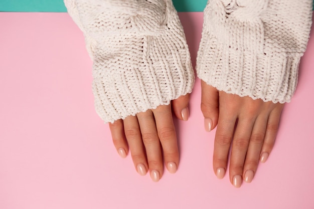 Die Hände der schönen Frau auf rosa Hintergrund. Winterpflege, Haut, Spa-Konzept