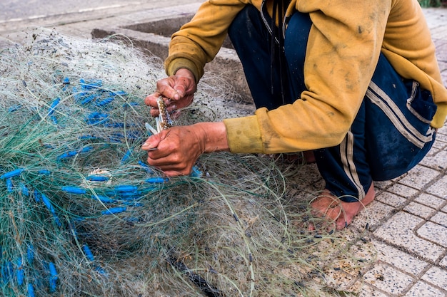 Die Hände des alten Fischers entwirren die Fischernetze Nha Trang