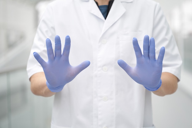 Die Hände des Arztes trugen medizinische Handschuhe in einer Stoppgeste