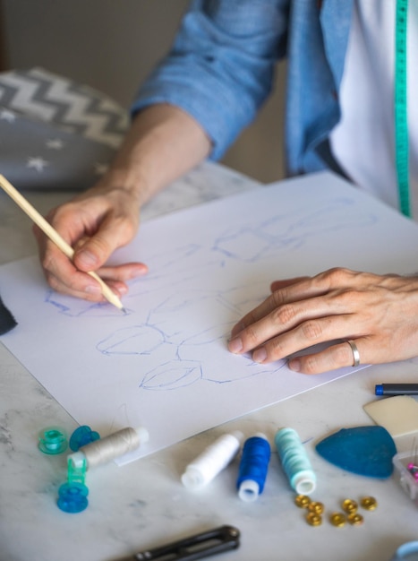 Die Hände des autodidaktischen Schneiders sind auf seiner Skizze Hand mit Bleistift Ein DIY-Designer zeichnet eine Skizze für ein neues Kostümprojekt. Nahaufnahme des Lebensstils mit selektivem Fokus