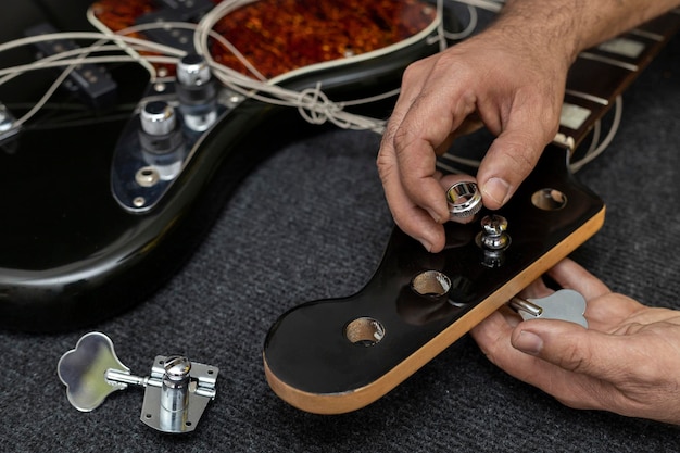 Die Hände des Gitarrenbauers platzieren und justieren den Wirbel eines E-Bass