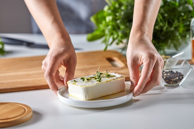 Die Hände des Mädchens halten einen Teller mit Weichkäse mit grünen Sprossen auf einem weißen Tisch mit Dill und Petersilie, kopieren Platz für Text. Gesundes Essen