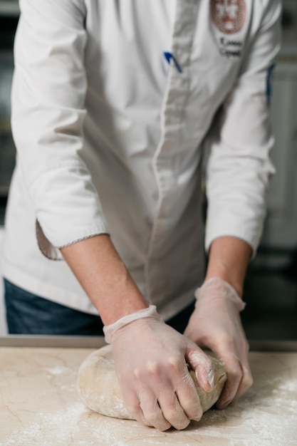 die hände des männlichen kochs kneten den teig zum backen von brot. Foto in hoher Qualität