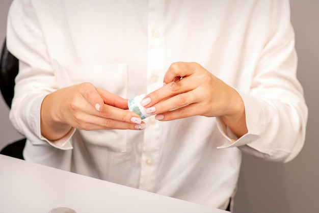 Die Hände des Maniküremeisters mit schöner Maniküre-Holding-Box mit Nagelpailletten im Nagelstudio.