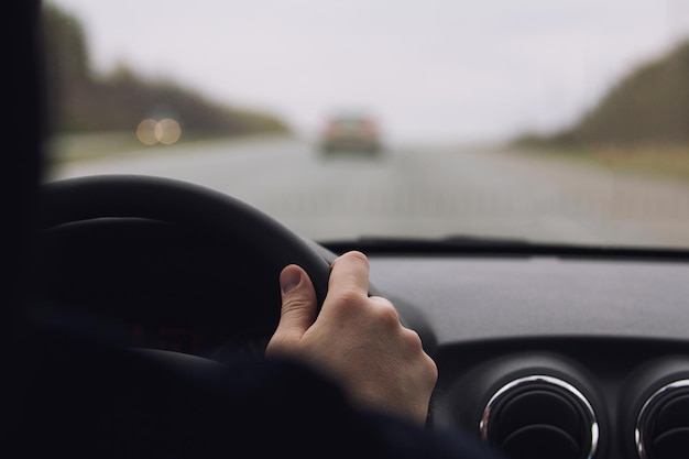 Die Hände des Mannes auf einem Rad - in einem Auto auf der Autobahn, Nahaufnahme