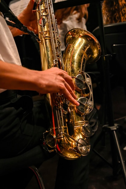 Die Hände des Mannes, die das Saxophon im Orchester spielen