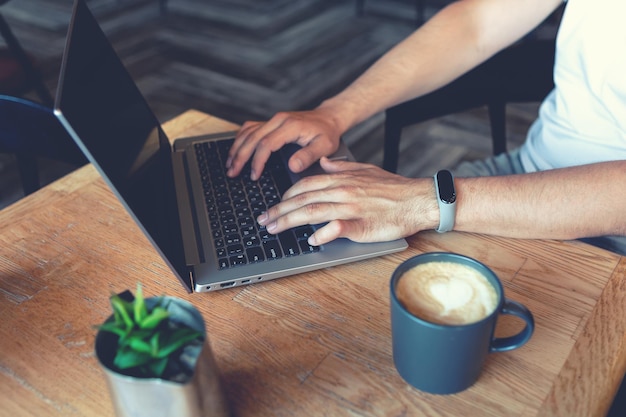 Die Hände des Mannes drucken auf dem Computer im Café. Nahansicht