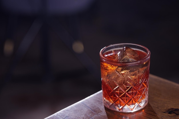 Die Hände des Menschen gießen Negroni aus einem Krug in das Glas Bar aus einer Bar