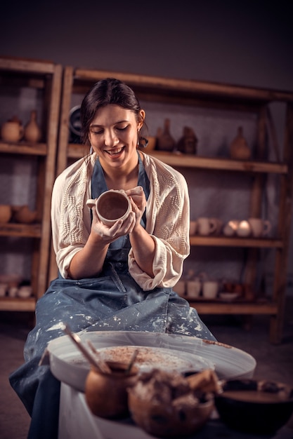 Die Hände des Töpfers sind wie eine Tasse aus Ton geformt. Der Prozess der Herstellung von Keramik auf einer Töpferscheibe.