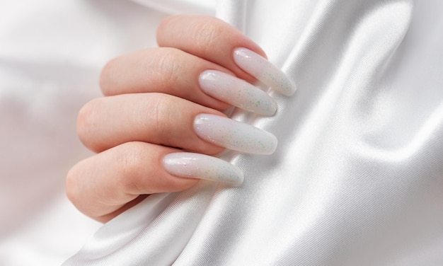 Die Hände einer Frau mit einer Maniküre darauf sind die Nägel in weißer Farbe lackiert