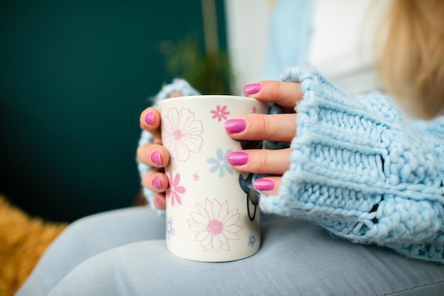 Die Hände einer Frau umschließen einen Becher mit heißem Getränk