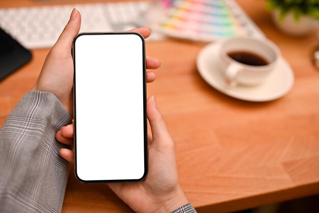 Die Hände einer Grafikdesignerin, die ein Mockup des weißen Smartphone-Bildschirms halten