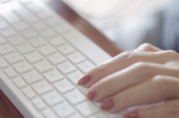 Die Hände einer Person tippen auf einer Tastatur mit dem Buchstaben t darauf.