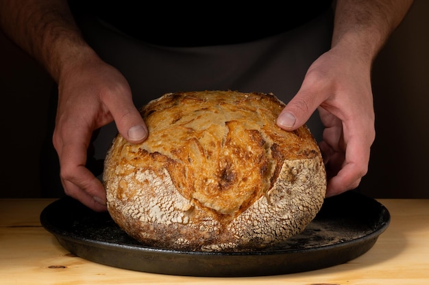 Foto die hände eines jungen mannes, der auf einem tablett sauerteigbrot manipuliert