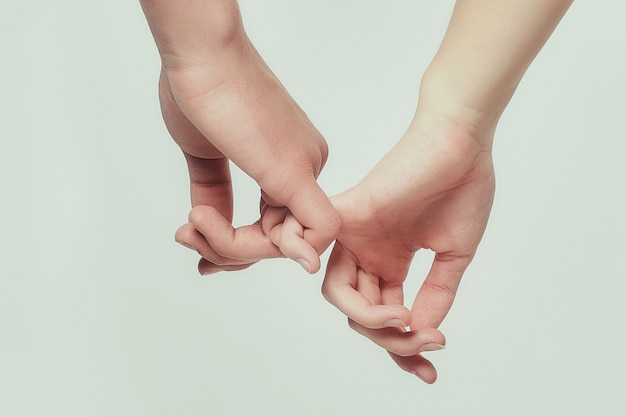 Die Hände eines Jungen und eines jungen Mädchens greifen nacheinander. weißer Hintergrund