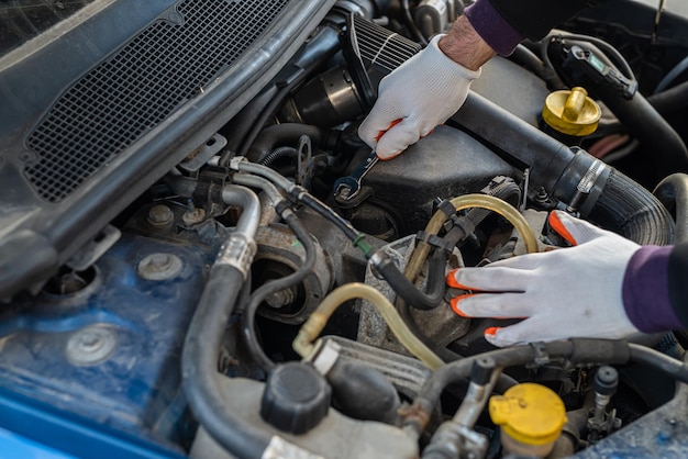 Die Hände eines starken Mechanikers in Handschuhen reparieren das Auto unter der Motorhaube Autoreparaturkonzept Autoinspektionskonzept