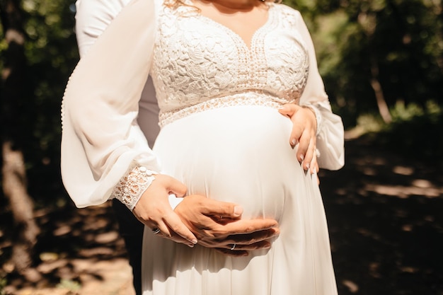 Die Hände eines verliebten Paares umarmen den Bauch einer schwangeren Frau unter Sonnenlicht Schwangerschaft Schwarz-Weiß-Foto