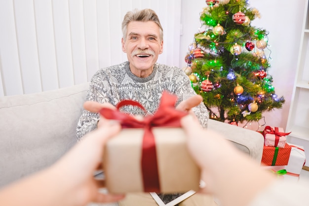 Die Hände mit einer Geschenkbox für einen glücklichen alten Mann