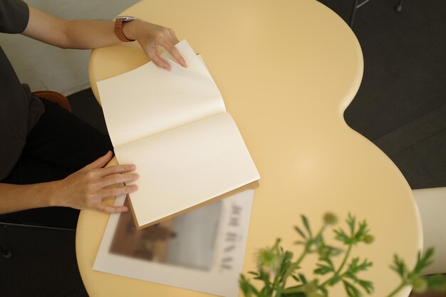 Die Hände öffnen ein leeres Buch oder eine Zeitschrift auf einem Holztisch