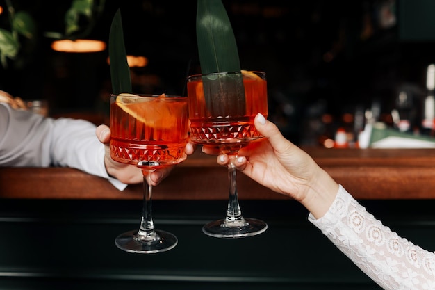 Die Hände von Frau und Mann klingeln mit Gläsern Spritz-Cocktail-Paar, das feiert