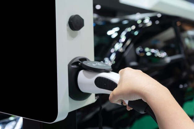 Die Hände von Frauen, die Energieladegeräte für Elektroautos halten Hintergrund ist das Erscheinungsbild des Autos