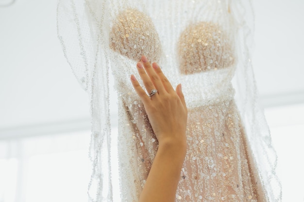 Die Hand der Braut, die Details ihres Hochzeitskleides berührt