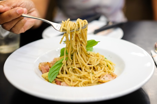 Die Hand der Frau, die Gabel für würzigen Speck u. Schinken der Spaghettis hält